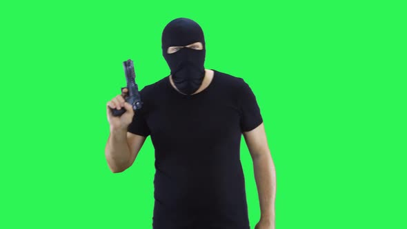 A man in a black mask holds a gun in his hand and goes forward.
