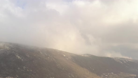 High above mountain top in clouds 4K drone video alt