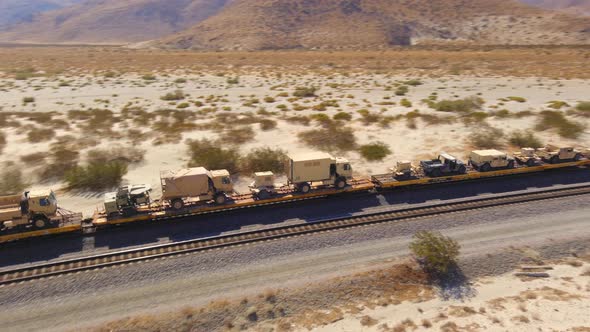 United States Army train transporting military vehicles through the desert, aerial tracking shot as alt