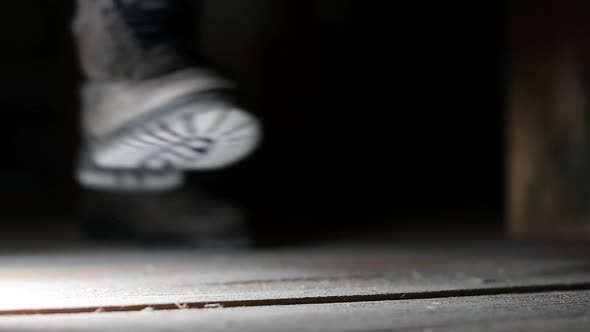 a man walks past the camera, raising dust in the attic into the air alt