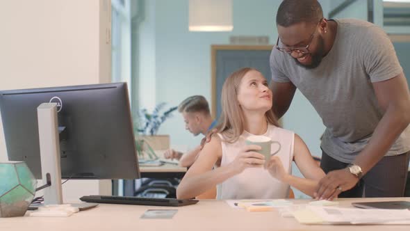 African Guy Bringing Coffee To Girl at Co-working alt