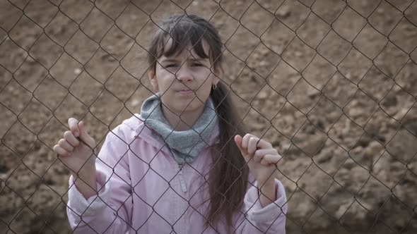 Sad child behind an iron fence.  alt