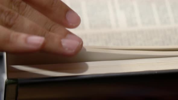 Close-up side view of a person turning the pages of a book alt