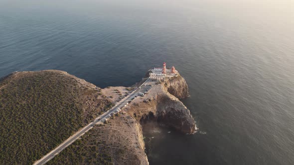 Cape Sao Vicente Lighthouse against the Atlantic Ocean, Sagres, Algarve.  Sunset aerial wide shot alt