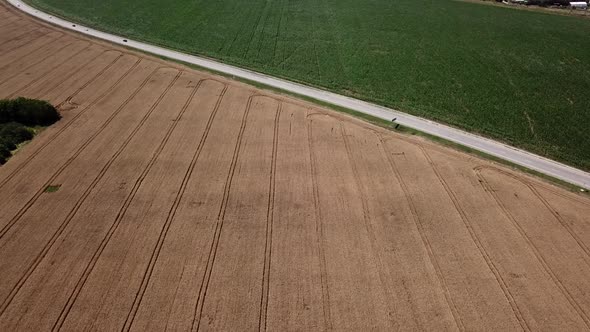 Aerial View of Highway Road Between Meadow and Agricultural Field. alt