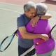 Video of happy biracial senior couple embracing on tennis court