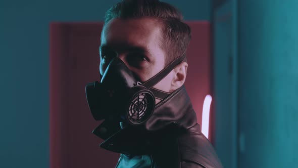 Portrait of Brutal Man in Respirator Turns to Camera at Night Over Neon Lights in the Style of alt