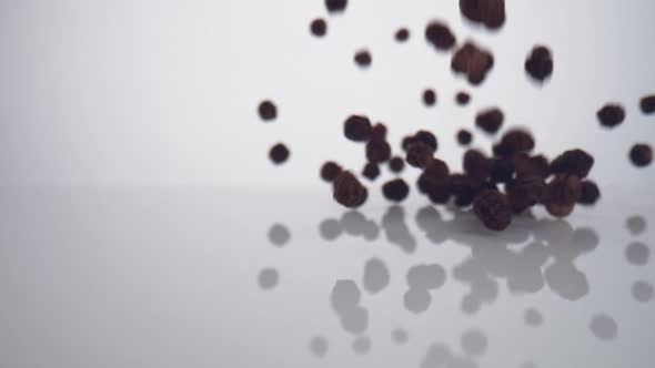 Camera follows black pepper falling on surface. Slow Motion. alt