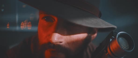 Close up of man looking into camera holding vintage camera alt