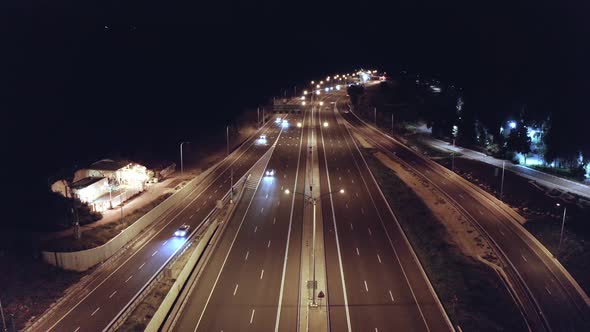 Drone aerial shot of night traffic on a highway showing cars and lanes of light with bridges