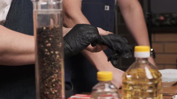 Chef in Restaurant Wears Black Latex Gloves to Prepare Gourmet Dish for His Guests alt