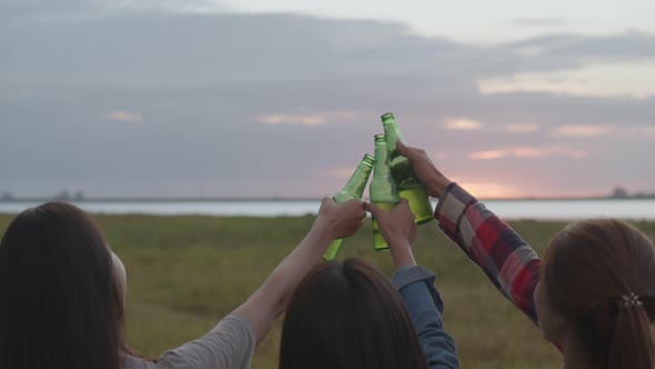 Asian woman happy friends camping in nature having fun together drinking beer and clinking glasses.