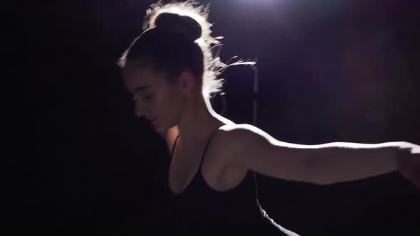 Beautiful Flexible Ballerina Standing on Her Pointe Ballet Shoes in Spotlight on Black Background alt