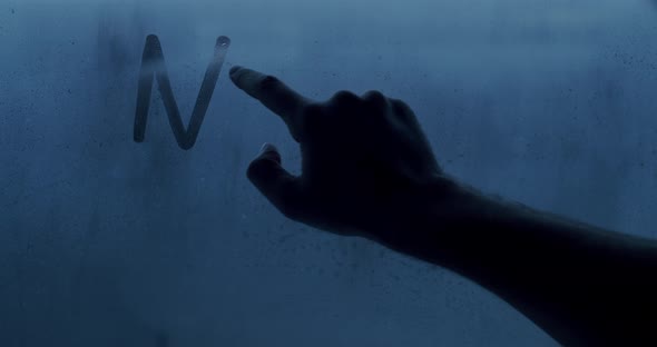 A man's hand writes a No War message on the window with his finger.Stop War text alt