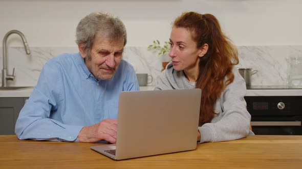 Smiling Young Attractive Woman Discussing Internet Shopping with Older Mature Father Looking at alt