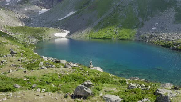 Aerial view. Alone woman traveler watching on turquoise mountain lake Arkhyz nature Caucasus Russia