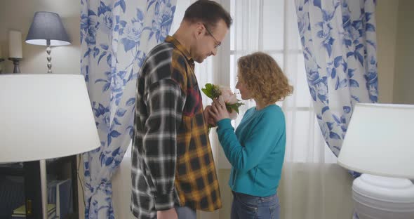 Young Man Giving Flowers To Girlfriend at Home alt