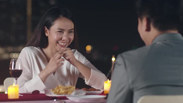 Young asian couple romantic dinner in rooftop restaurant at night city with happy moment celebrate alt