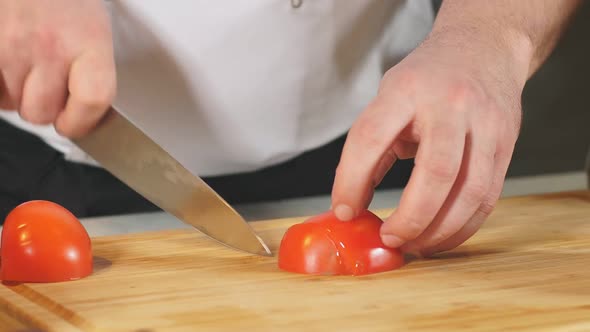 Man Person Cutting Tomato with Sharp Knife on a Wooden Board