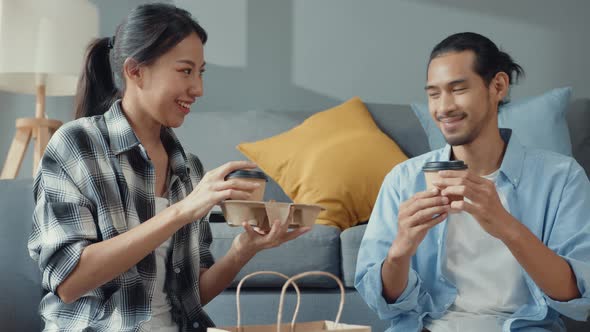 asian young attractive couple man and woman sit at new home drink coffee relax and talk smile.