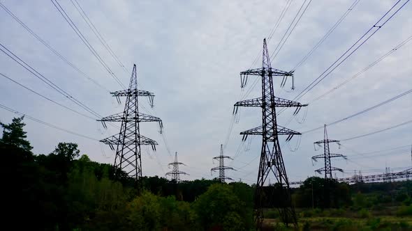 Electricity pylons bearing the power supply across a rural landscape during sunset. Selective focus. alt