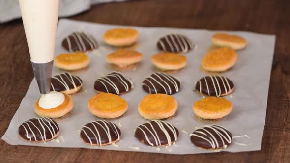 Making Homemade Cookies with Apricot Jam and Whipping Cream. Hand with Confectionery Bag Squeezing alt
