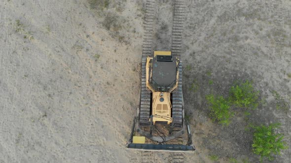 Top Aerial View on Tracked Bulldozer Rides on Sandy Road at Construction Site alt