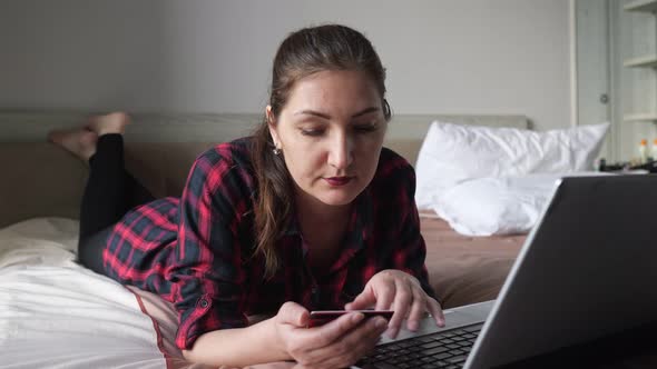 Attractive Long Haired Lady Looks at Credit Card and Types alt
