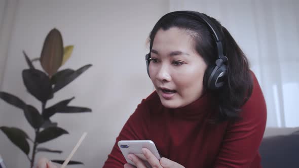 Businesswoman redshirt using a tablet with headphone for meeting online at home alt