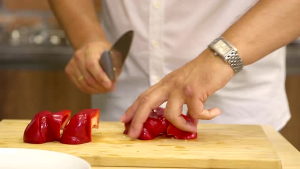 Amateur Cook Cuts Bell Pepper on Wooden Chopping Board in Kitchen Close Up