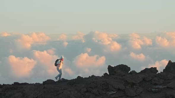 Female Hiking Alone Edge of High Mountain with Cinematic Pink Clouds View alt