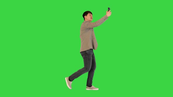 Young Asian Man Walks Making a Video Call on a Green Screen Chroma Key alt