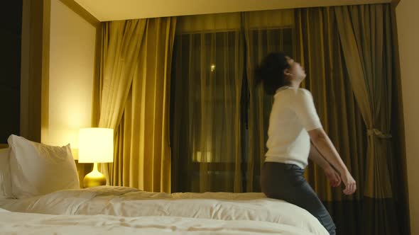 asian female woman jumping on bed resting after successful travel journey