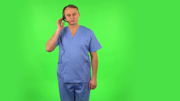 Medical Man Talking on Headphones at Support Service. Green Screen alt