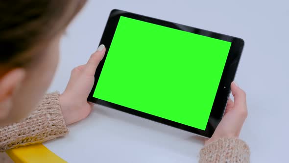 Woman Looking at Tablet Computer with Green Screen in Cafe