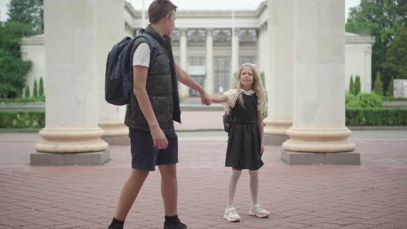 Wide Shot Portrait of Schoolboy Pulling Hand of Stubborn Schoolgirl Unwilling To Go To Studying alt