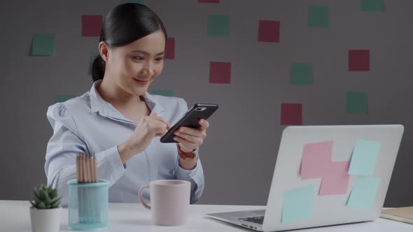 Asian woman happy smiling reading news on smart phone