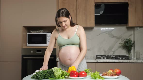 Pregnant Woman Strokes Belly Cutting and Eating Bell Pepper alt