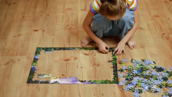 Closeup of a Playing Child Sitting on the Floor and Collecting Puzzles alt
