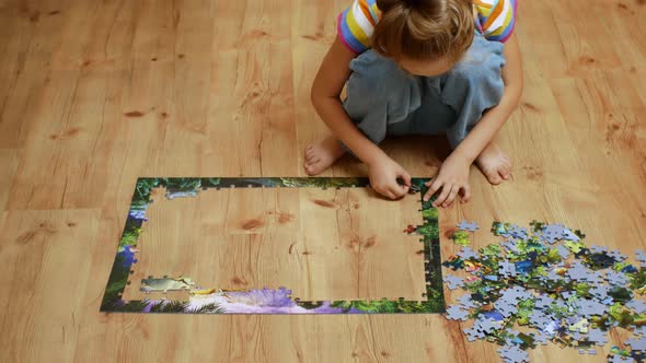 Closeup of a Playing Child Sitting on the Floor and Collecting Puzzles