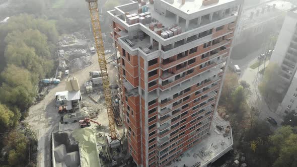 Birds eye view on tower crane in fog standing next to residential building. alt