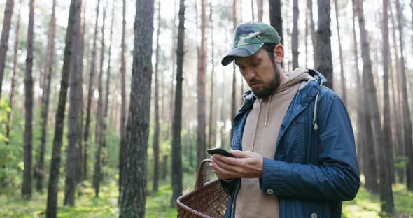 Young Man Mushroom Picker Walking in Unknown Forest Looking for Mushrooms Stands in Middle of Trees alt
