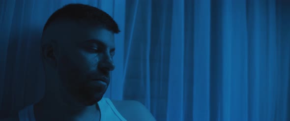 Close up of a depressed man sitting in the bedroom, staring to nowhere alt