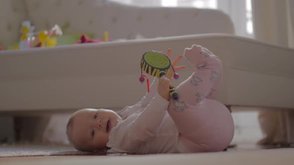 Baby girl in warm clothes playing on the floor alt