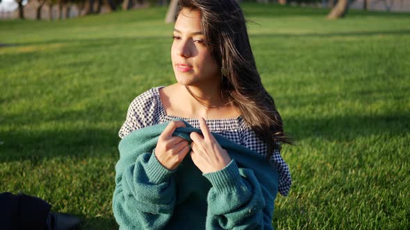 Close up of a pretty hispanic woman trying to get warm and cozy with her sweater in cold season wind alt