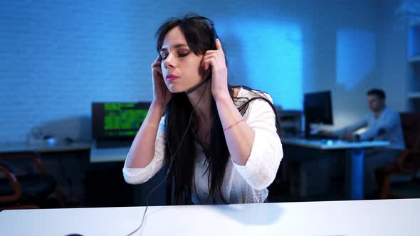 Serious Slim Beautiful Woman Putting on Headphones and Typing on Keyboard alt