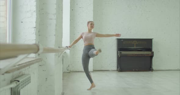 Ballet Dancer Performing Passe Exercise at Barre alt