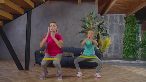 Sporty Fit Mom and Child Doing Banded Squat Indoors alt