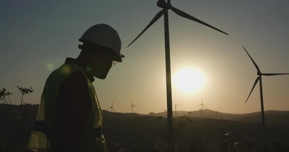 A Young Engineer Inspects the Windmills Hiding His Hand From the Sun alt