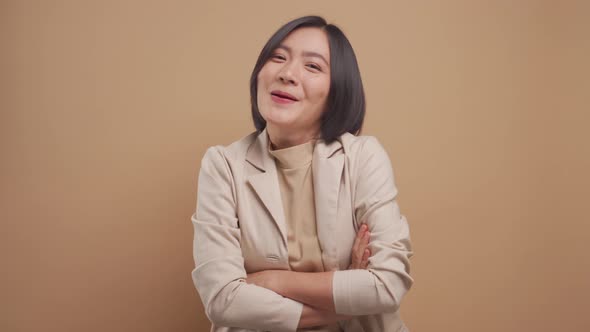 Happy asian business woman standing and laughing standing isolated over beige background. 4K video